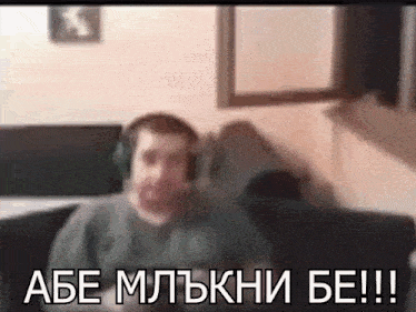 a man wearing headphones is sitting on a couch with the words abe mltknhi be !!! above him