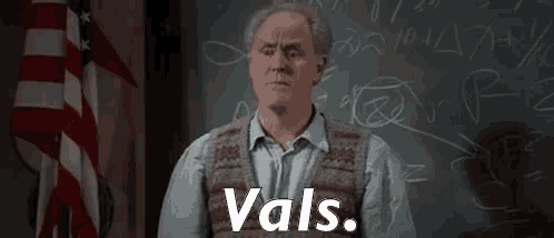 a man is standing in front of a blackboard in a classroom with the word vals written on it .
