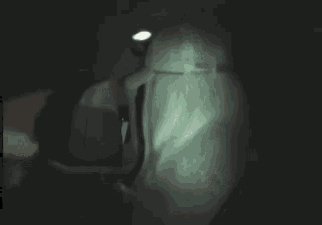 a person wearing a white hat and a hoodie is standing in the dark