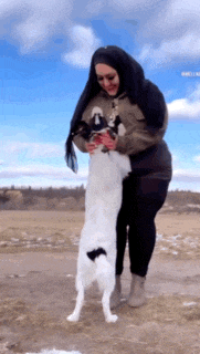 a woman in a hijab is holding a dog in her arms