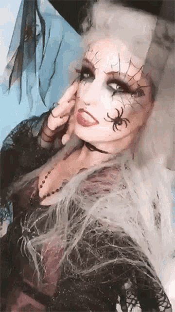 a woman in a witch costume has spiders painted on her face