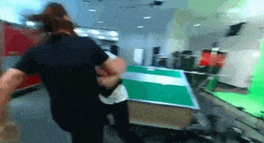 two people are playing ping pong in a room with a green background