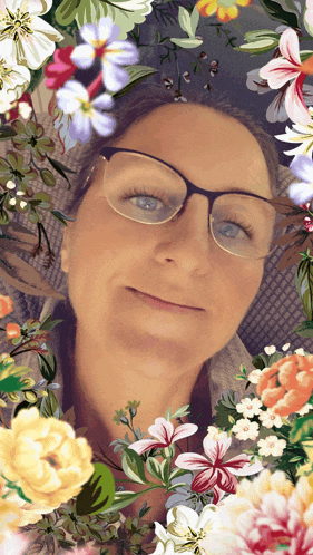 a woman wearing glasses is surrounded by flowers and leaves
