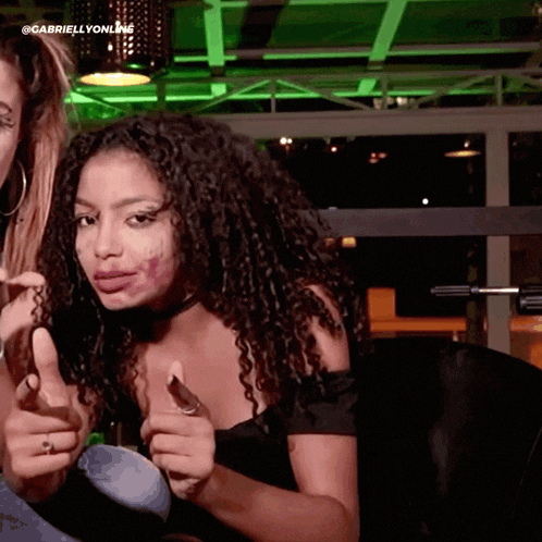 a woman with curly hair giving a thumbs up