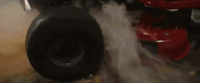 a close up of a tire on a red car with smoke coming out of it .
