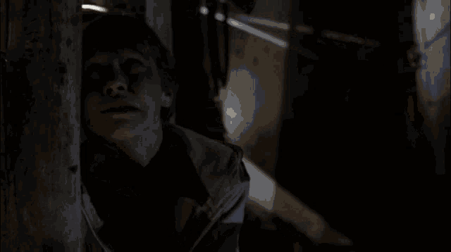 a man with his eyes closed is standing in a dark room next to a wall