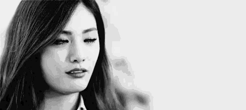 a black and white photo of a woman with her eyes closed and a serious look on her face .