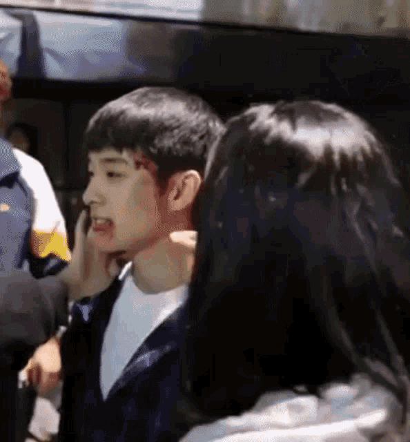 a man and a woman are standing next to each other and the woman is holding the man 's face .