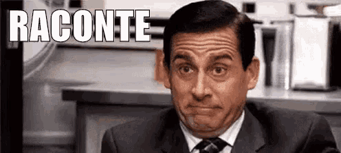 a man in a suit and tie is making a funny face while sitting in front of a counter .