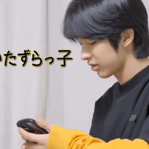 a young man in a yellow sweater is looking at his phone