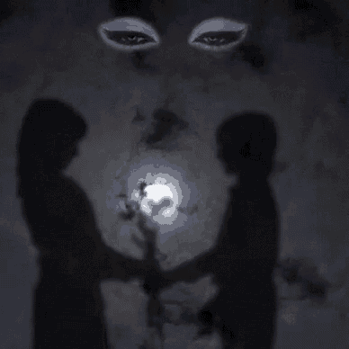 two people are holding hands in front of a full moon in a dark room .