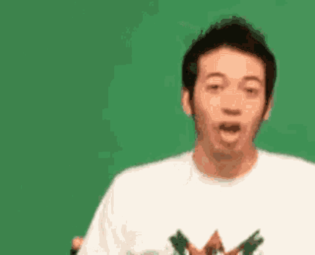 a man in a white t-shirt is making a surprised face with his mouth open .