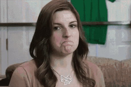 a woman is making a funny face and wearing a necklace .