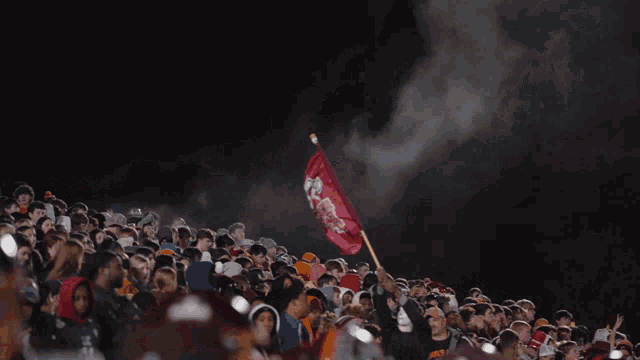 a crowd of people watching a football game with a flag that says texas tech university