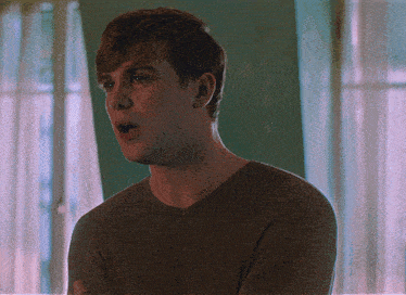 a man with a surprised look on his face is wearing a brown shirt
