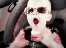 a baby wearing sunglasses is sitting in a car seat with his mouth open .