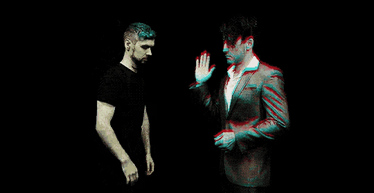 two men are giving each other a high five in a dark room