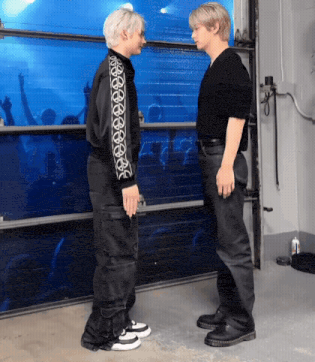 two men are standing next to each other in front of a blue door .