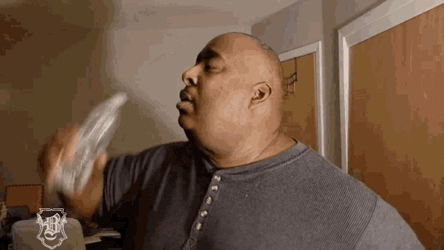 a man in a gray shirt is holding a bottle in his hand .