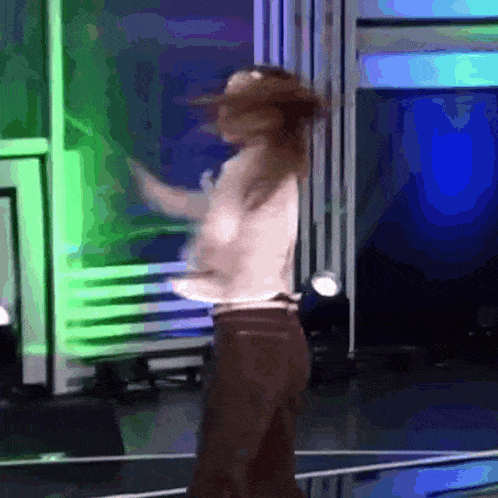 a woman is dancing on a stage in front of a green and blue wall .