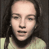 a close up of a woman 's face with headphones on and a green shirt .