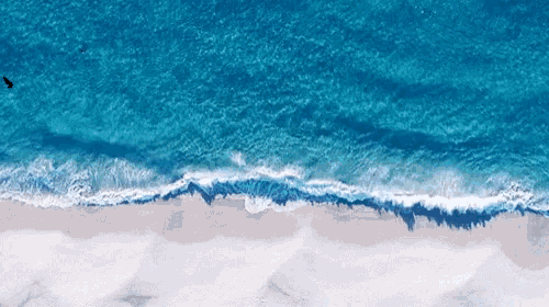 an aerial view of a beach with waves crashing on the shore