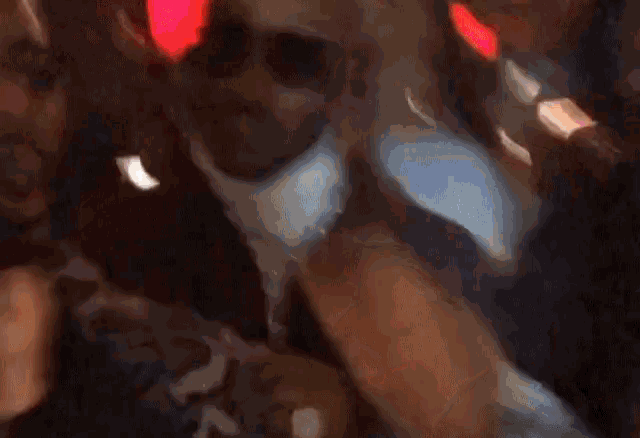 a blurry picture of a man wearing sunglasses and a white turtleneck