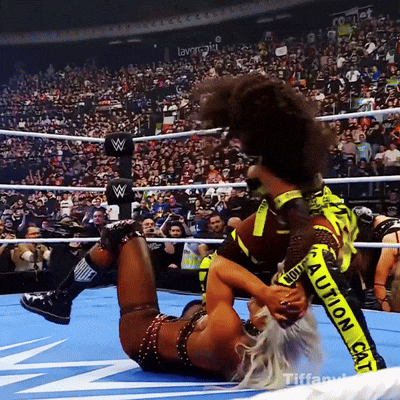 a woman in a wrestling ring has a yellow caution tape on her pants