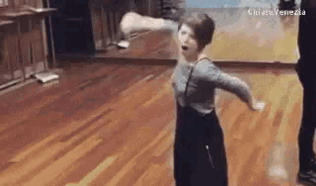 a woman is dancing in a room with a wooden floor .