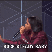 a woman is singing into a microphone with the words rock steady baby behind her