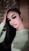 a woman with long black hair is wearing a white sweater and taking a selfie .