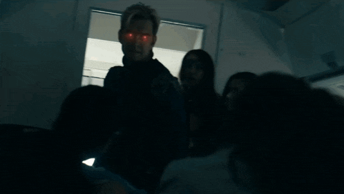 a man with red eyes is standing in front of a group of people .