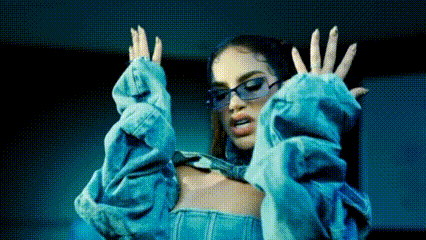 a woman wearing sunglasses and a blue sweater is dancing .