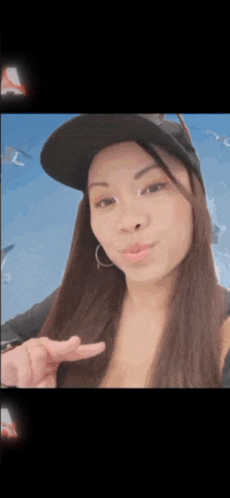 a woman wearing a black hat and hoop earrings is pointing at the camera
