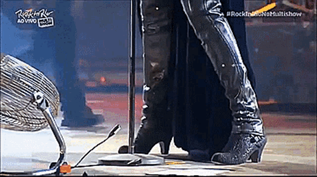 a person standing on a stage with a fan and a sign that says rock in rio ao vivo