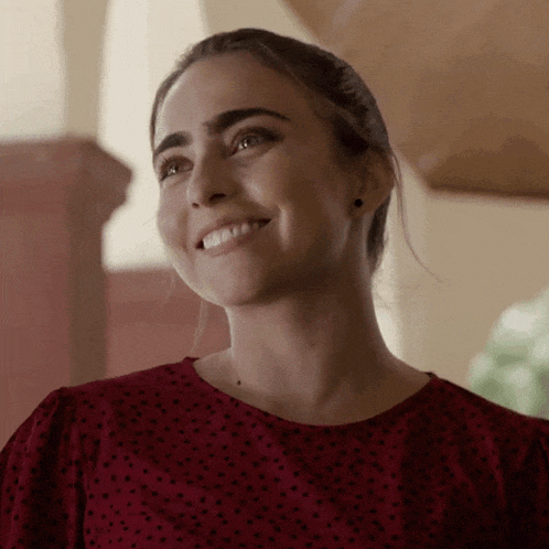 a woman wearing a red polka dot shirt smiles for the camera