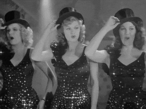 three women in top hats and sequined dresses singing