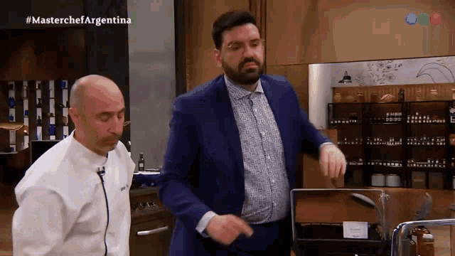 a man in a suit stands next to another man in a chef 's jacket with the words masterchef argentina on the bottom right