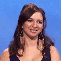 a woman wearing earrings and a black top is smiling