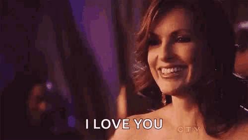 a woman is smiling and saying `` i love you '' while standing in a dark room .