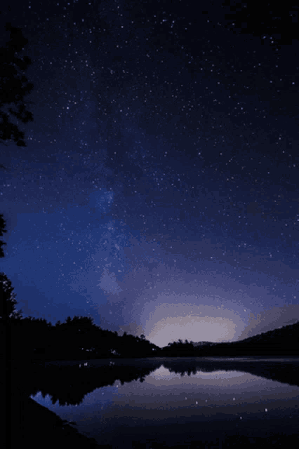 a starry night sky over a body of water