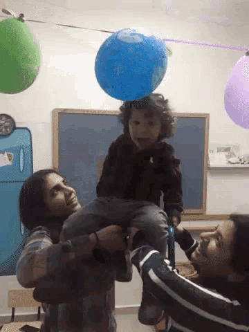 a woman is holding a child in her arms with a blue balloon on top