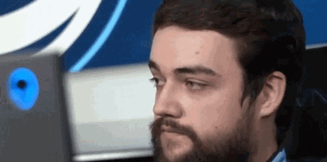 a man with a beard is sitting in front of a computer screen .