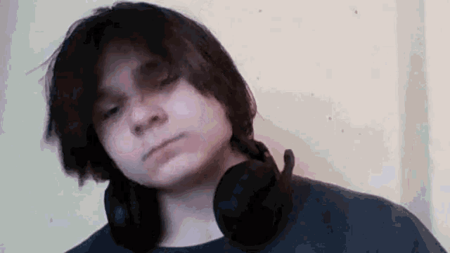 a young man wearing headphones looks at the camera