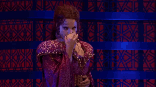 a woman in a purple dress is holding a pearl in her hand .