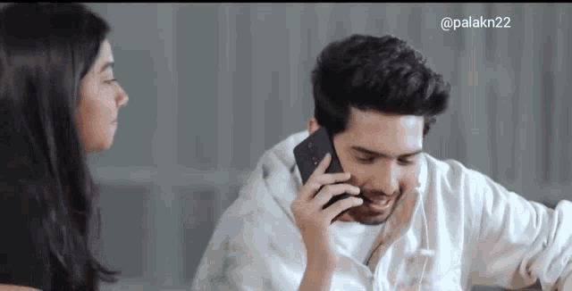 a man is talking on a cell phone while a woman looks on .