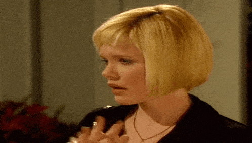 a woman with short blonde hair is wearing a black jacket