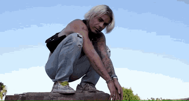 a man squatting down with a tattoo on his arm that says ' i love you ' on it