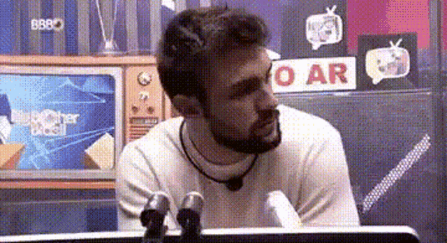 a man with a beard is sitting in front of a microphone in a room .