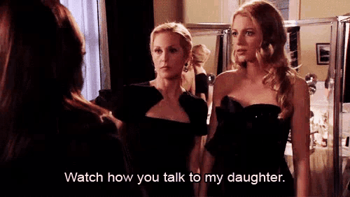 two women in black dresses are standing next to each other and one of them is talking to her daughter .